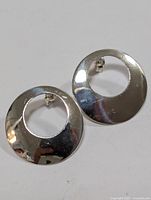 Pair of polished round silver earrings with hollow cut-out center shown from above