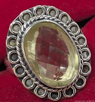 Close-up of sterling silver lemon quartz ring showing faceted stone and ornate silver bezel setting with looped decoration and twisted rope detail.