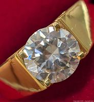 Close-up front view of silver ring with round moissanite stone in yellow-gold tone band