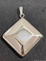 Front view of silver square pendant showing polished reflective surface and concave design.