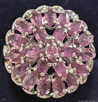 Close up front view of circular ring with marquise pink stones in cluster setting on a silver base.