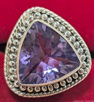 Close-up image showing the faceted triangular amethyst stone set in silver with beaded detail surround.