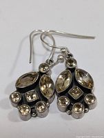 Pair of sterling silver earrings with multiple citrine stones, arranged with round, marquise, and square cuts. Dark oxidized silver background for contrast.