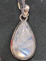 Close-up of teardrop moonstone pendant set in silver, showing the blue sheen and reflective surface.