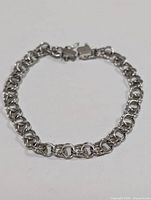 Top view of sterling silver double interlocking link chain bracelet arranged in circle showing box clasp.