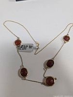 Full view of the necklace laid out flat, showing chain and six red onyx stones with silver bezels