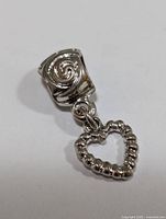 Close-up front view of the silver heart dangle bead charm showing the swirl detail on the bead.