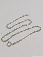 Full view of the silver chain bracelet laid out, showing its length and link style.