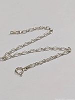 Close-up of silver chain bracelet showing oval links and spring ring clasp.