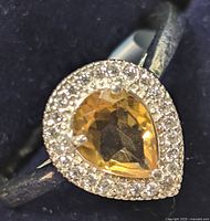 Close-up image of sterling silver ring with pear-shaped citrine surrounded by cubic zirconia stones.
