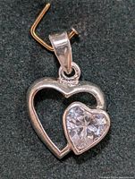 Close-up of the silver heart-shaped pendant showing the dual-heart design with the smaller heart set with a clear cubic zirconia stone.