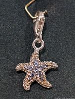Close-up photo of starfish shaped silver pendant with cubic zirconia.