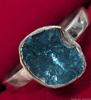 Close-up showing the rough texture and deep blue color of the irregular stone set in the silver band.
