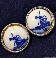 Close-up of one silver earring showing the blue windmill design on white background with silver frame