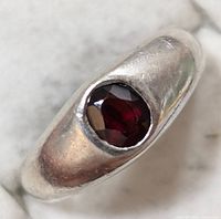 Close-up of the ring top showing oval faceted garnet stone in smooth silver bezel setting