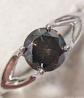 Close-up view of round black moissanite gemstone set in a silver ring from front angle.