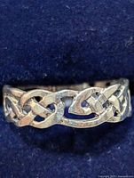 Front view of silver ring showing Celtic knot design against blue background.
