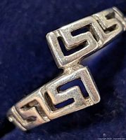 Close-up photo of silver ring showing geometric, Greek key style design on the band, size 6.5.