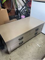 Full side view of beige wood coffee table showing three drawers and metal handles.