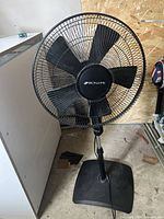 Front view of black Bionaire pedestal fan showing five blades, wire cage, and base with minor scuff marks.