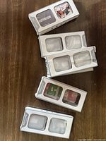 Top-down view of multiple black plastic Apple Watch cases in white boxes with plastic windows showing cases inside, some packaging torn or damaged.