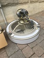 Top-down view of ceiling fan and light fixture showing the fan blades, mounting wires and protective grill. Visible control buttons on fan housing.
