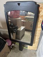 Frontal view of the contemporary black wood frame wall mirror showing carved top detail and reflective glass.