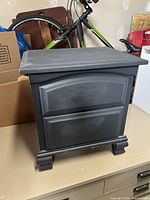 Front view of gray wooden nightstand showing two drawers with raised panel design and decorative base molding.