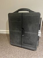 Closed black plastic carrying case with Jobmate logo and handle resting on carpet.