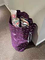 Photo of a large purple reusable bag containing several gift bags and rolls of wrapping paper.