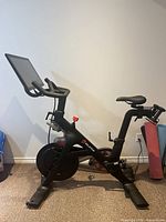 Full view of the Peloton stationary bike in black with screen, saddle and base visible