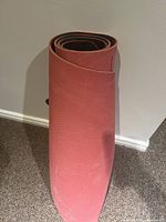 Rolled red yoga mat standing up, showing textured surface and signs of moderate use