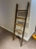 Full view of rustic wooden decorative ladder leaning against a wall showing overall height and structure.