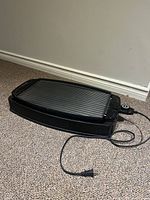 Full view of Salton electric grill with ribbed grilling surface and power cord.