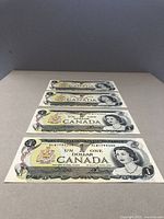 Four sequential $1 Canadian Bank of Canada notes displayed flat in a row to show front design and condition.