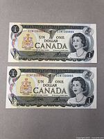 Two sequential $1 Canadian bank notes laying flat, showing front design with portrait of Queen Elizabeth II and serial numbers ECN130588 and ECN130589.