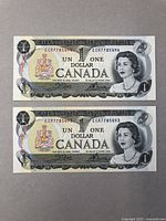 Two $1 Canadian bank notes featuring Queen Elizabeth II portrait and Canadian coat of arms in sequential order, both in protective cases
