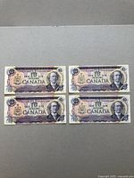 Four Canadian $10 bank notes from 1971 laid out flat showing front side with portraits and denomination.