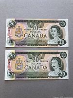 Front side view of two Canadian $20 bank notes from 1979 series showing Queen Elizabeth II portrait, coat of arms, and denomination details.