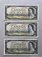 Front view of three Canadian twenty-dollar banknotes showing Queen Elizabeth II portrait and serial numbers.