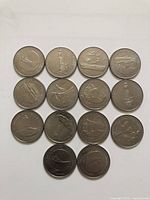 Photo of the reverse sides of 16 Canadian quarters showing various commemorative designs including wildlife, cultural symbols, and landmarks.