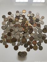 Top view of a large assortment of international coins scattered loosely showing various sizes, metals, and designs.