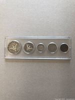 Five vintage American coins in a single plastic protective display case viewed from above.