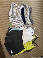 Photo showing two pairs of shorts (striped Lululemon shorts and solid black North Face shorts) laid flat on carpet.
