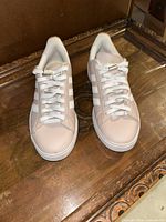 Front view of the pair of Adidas Grand Court Alpha shoes showing the light pink upper and white laces and sole.