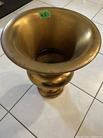 Top view of the brass coloured vase showing the flared opening with some tarnish and surface marks.