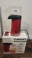 Front view of red Cuisinart hot air popcorn maker sitting on top of its original box.
