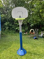 Full front view of Little Tikes basketball hoop with white backboard, green rim, net, and blue base on grassy outdoor area.