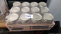 Top view showing 12 clear glass mason jars with silver metal lids securely packaged in a cardboard case.