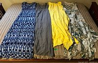 Four dresses laid out on a bed, various patterns and colors visible